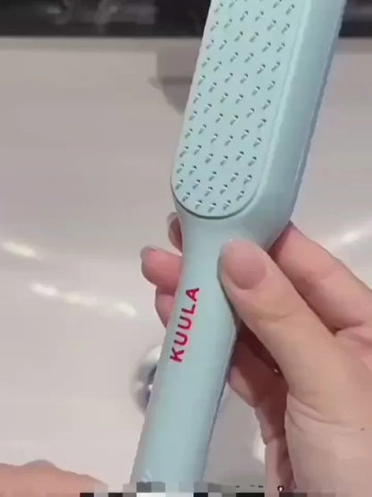 Light blue hairbrush with 'KUULA' branding held by a hand on a light background